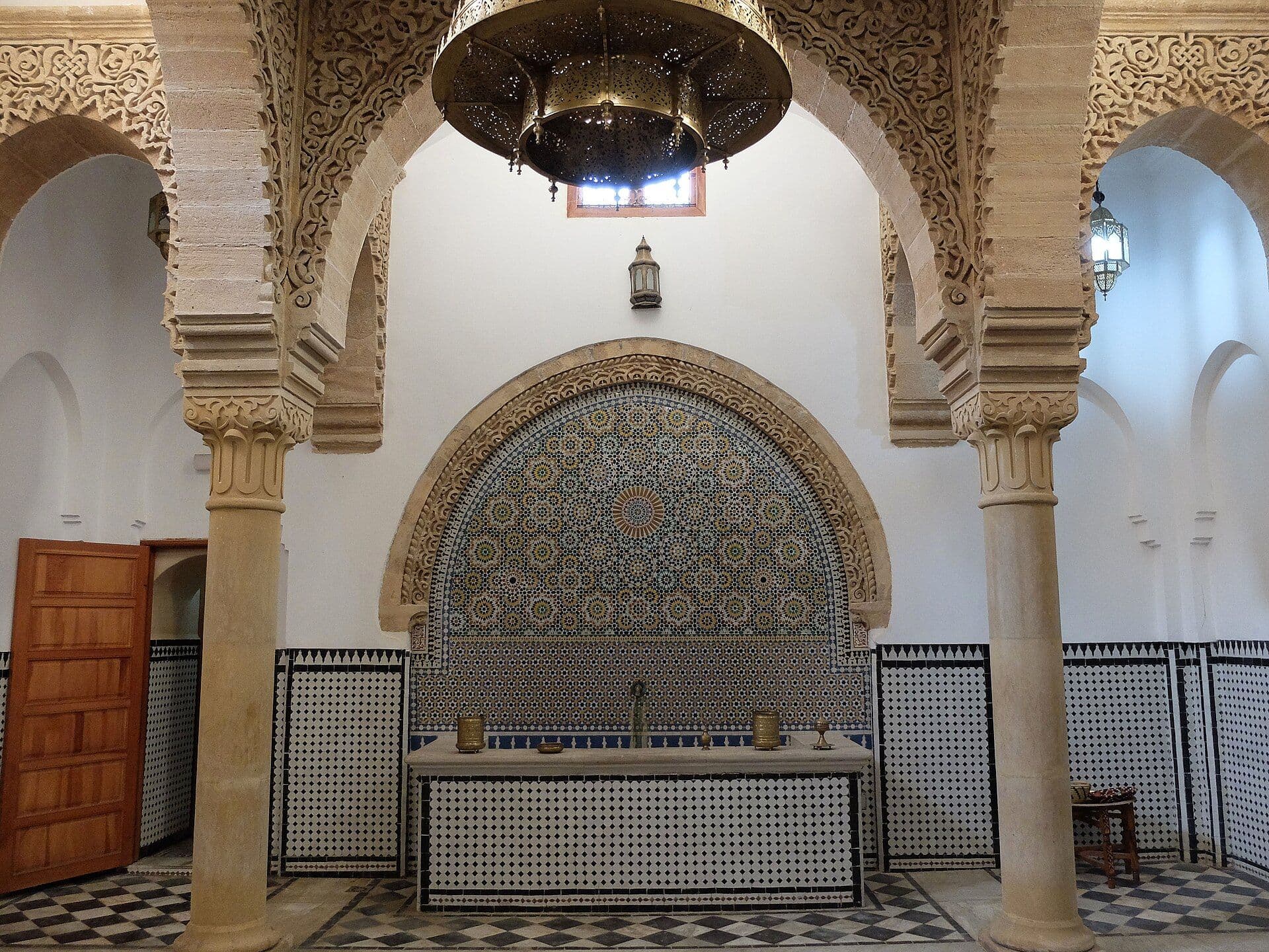 Interieur van een traditionele hammam met bogen, zuilen en een zellige-fontein