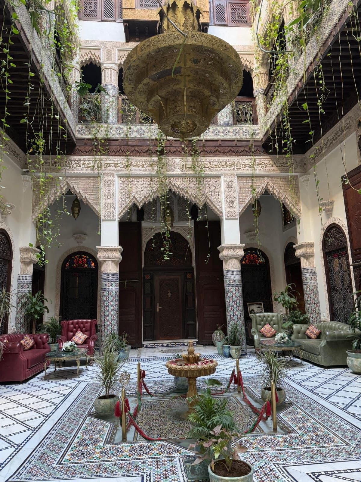 Binnenplaats van een riad met een fontein, zellige-tegels en houtsnijwerk