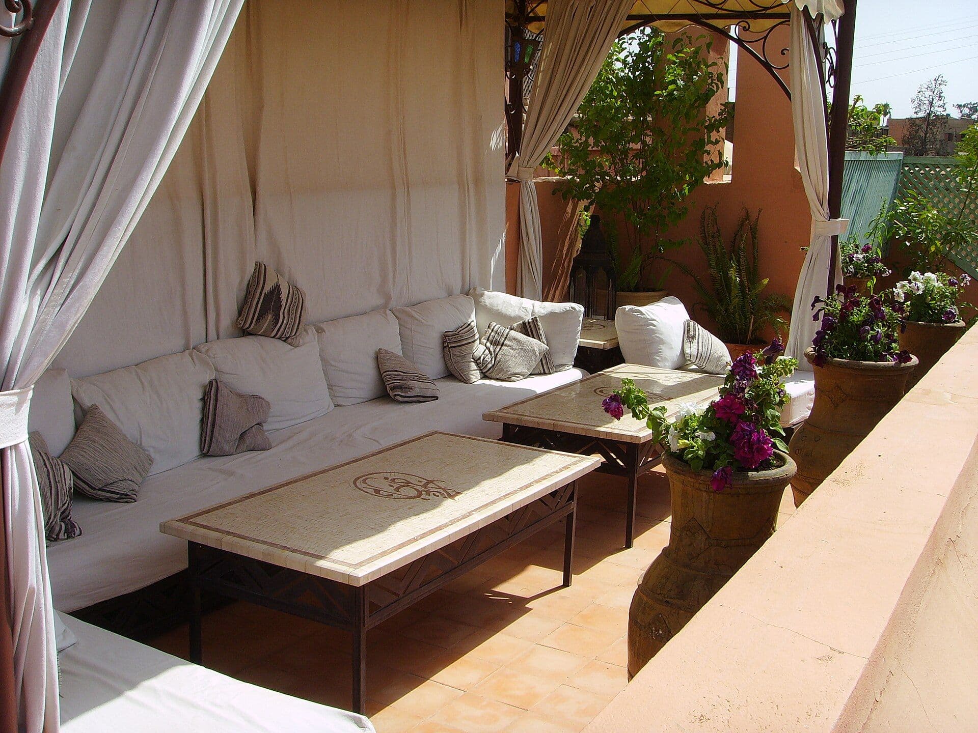 Dakterras van een riad in Marrakesh met witte kussens en bloemen