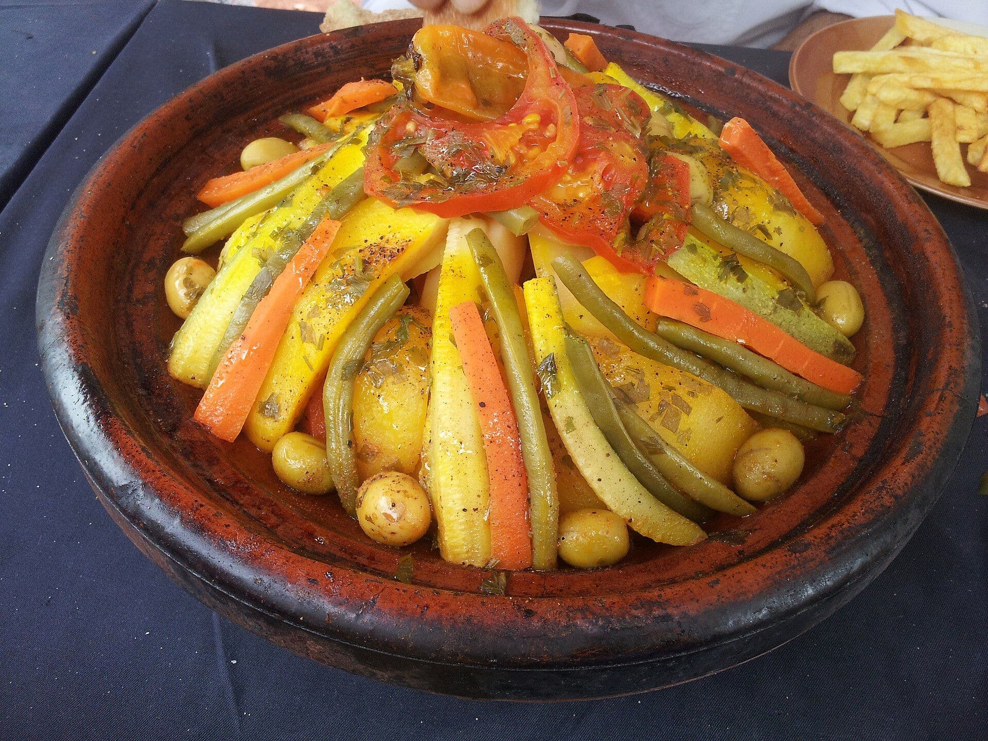 Groentetajine met wortel, courgette en olijven in een aardewerken schaal